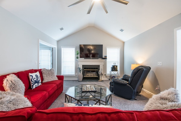 Living room with large flat screen tv, recliner and two couches and ceiling fan.