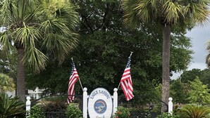 A sign with the text "Eagle Landing City of Hanahan" surrounded by a flower bed and two American flags. - Winter Discounts/We love pets! 6ft fenced in backyard and pet amenities. (Hanahan)