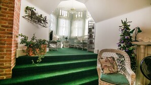 Una escalera con alfombra verde que lleva a una habitación con una silla de mimbre y un árbol de Navidad.