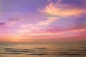 A sunset over a calm sea with a clear sky.