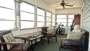 A sunlit room with wicker furniture, a ceiling fan, and a bicycle. - Cozy and friendly. All is Well - no damage (Clearwater Beach)