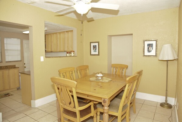 A dining room with a wooden table and chairs, a ceiling fan, and a floor lamp.