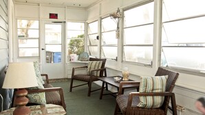 A sunroom with wicker furniture, a table, and a lamp. - Cozy and friendly. All is Well - no damage (Clearwater Beach)