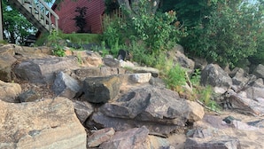 A rocky landscape with large boulders and a wooden staircase leading up to a red building.