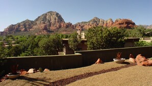A view of a mountainous landscape with a clear sky. There are buildings in the foreground with a garden area. - Beauty and the Beast Stunning Home, Stunning Views, Walk to Town Weekly Discount (Sedona)