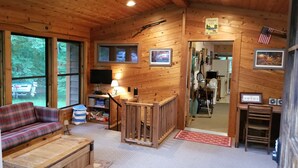 A cozy cabin interior with a plaid sofa, wooden coffee table, and a television.