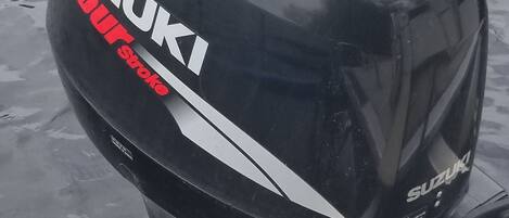 Motor fueraborda Suzuki de cuatro tiempos, negro, sujeto a una lancha.