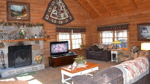 A log cabin interior with a stone fireplace, a television, a sofa, and a couch. - Southern Charm, beautiful cabin close to Pigeon Forge and Gatlinburg (Sevierville)