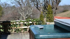 A hot tub in a backyard with a wooden deck, surrounded by trees and a wooden fence. - Southern Charm, beautiful cabin close to Pigeon Forge and Gatlinburg (Sevierville)