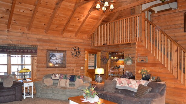 A log cabin interior with a wooden staircase, two sofas, a coffee table, and a fireplace. - Southern Charm, beautiful cabin close to Pigeon Forge and Gatlinburg (Sevierville)