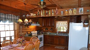 A wooden cabin kitchen with a dining table, chairs, and a refrigerator. - Southern Charm, beautiful cabin close to Pigeon Forge and Gatlinburg (Sevierville)
