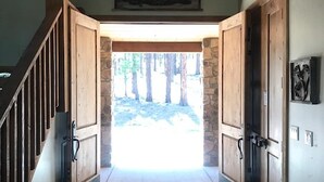 Un couloir avec des portes en bois menant à une entrée aux murs de pierre, un luminaire au plafond et un tableau encadré accroché au mur.