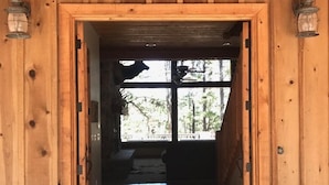 Une entrée en bois avec un sol carrelé qui mène à une pièce dotée d’une fenêtre et d’un banc.
