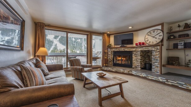 A cozy living room with a fireplace, a sofa, a coffee table, and a television.