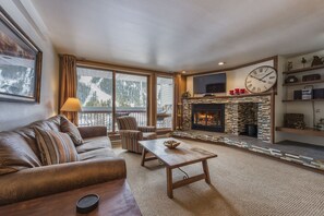 A cozy living room with a fireplace, a sofa, a coffee table, and a television.