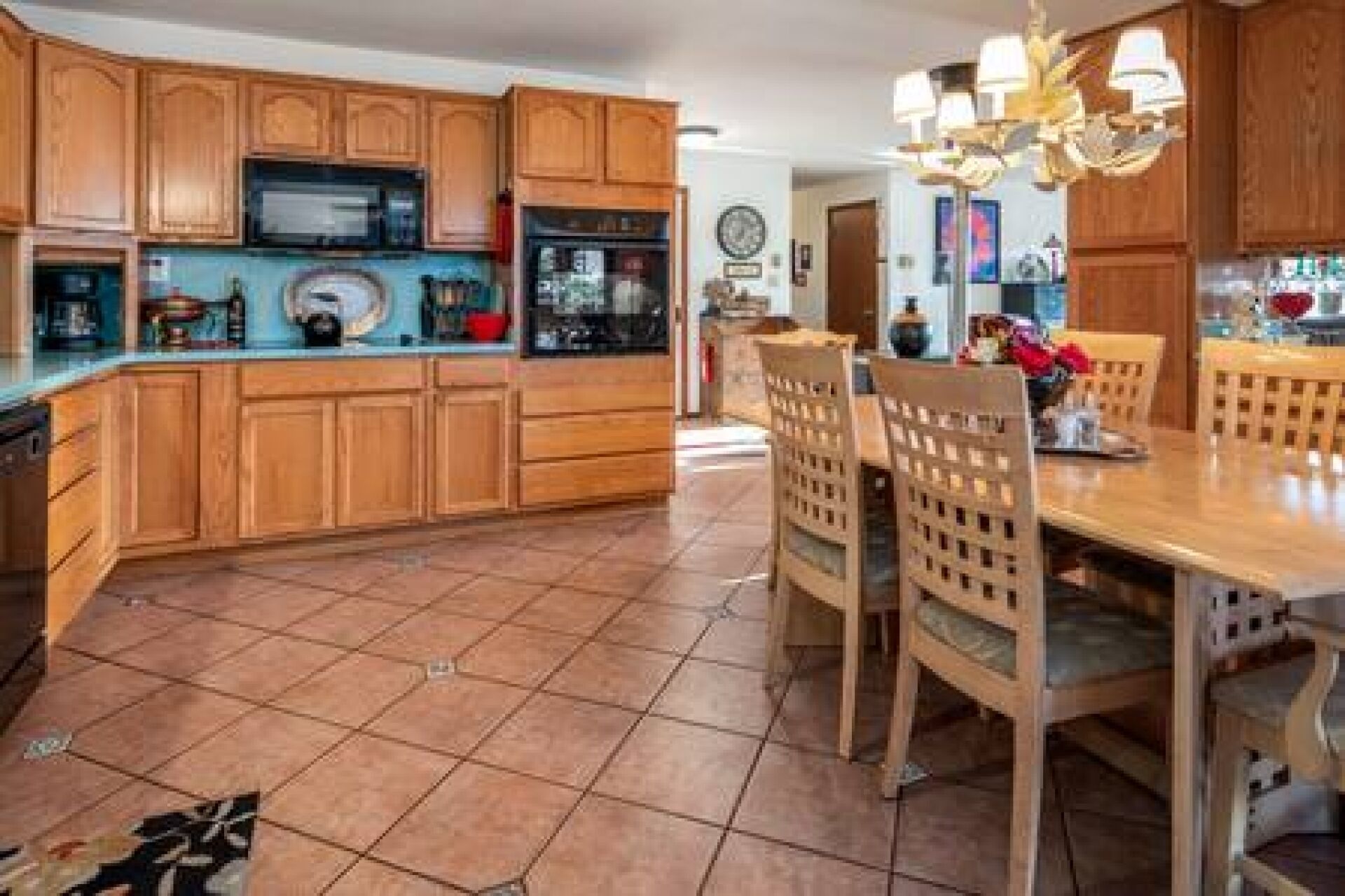 A kitchen with wooden cabinets, a microwave, and a dining area with chairs and a table.