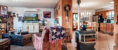 Un salon avec une cheminée, un coin repas et une cuisine dotée de meubles en bois.