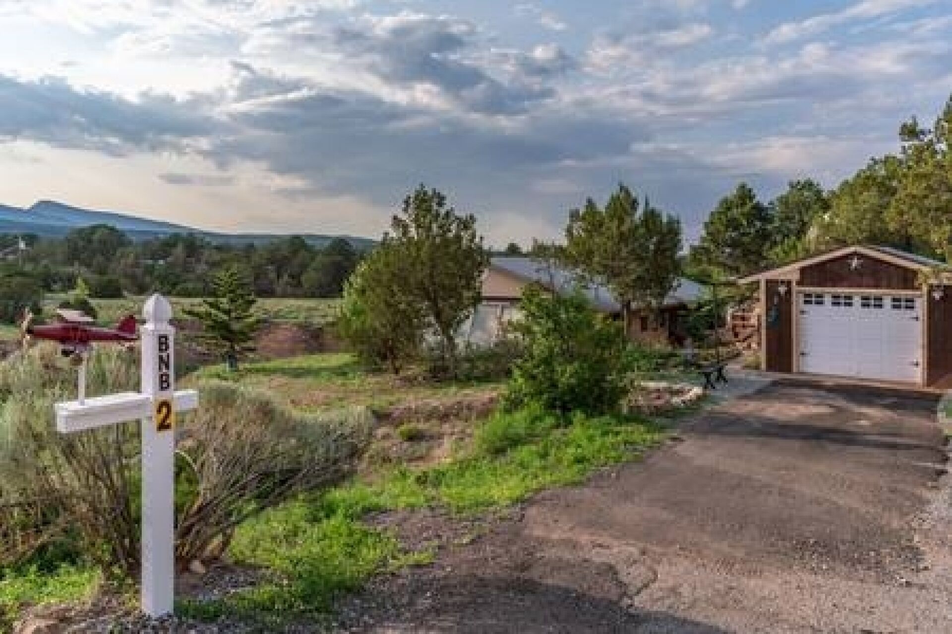 Una propiedad rural con camino de grava, garaje y un cobertizo pequeño.