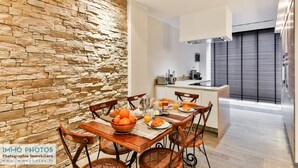 A modern kitchen with a stone wall, a dining area with wooden chairs, and a breakfast setup.