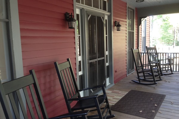 rocking chairs on the porch overlooking trees and pond.