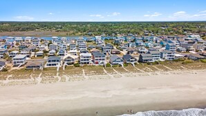 Une zone résidentielle côtière avec des maisons le long de la plage, une plage de sable et des vagues qui déferlent sur le rivage.