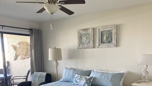 A bedroom with a bed, a ceiling fan, a nightstand, and a chair.