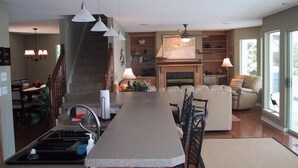 Una cucina moderna con isola centrale, zona pranzo con divano e una scala che conduce a un altro livello.