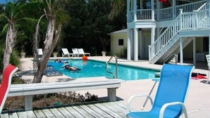 Area piscina con lettini, un pontile in legno e una struttura coperta con scale.