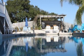 Ein Swimmingpool mit Liegestühlen und einer Pergola.