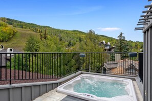A hot tub on a balcony with a view of a forested hillside. - Plaza Lodge | 7 - 4 Bedroom Gold with private rooftop Jacuzzi (Vail)
