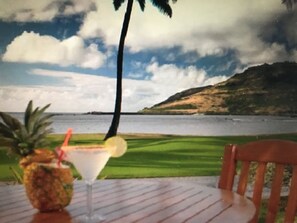 A table with a drink and a pineapple, a chair, and a view of a beach and ocean through a window. - Marriott Kauai Beach Club, Ocean View Studio.  Available Christmas Week! (Lihue)