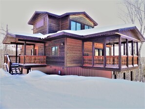 A wooden cabin with a balcony and a covered porch area.