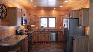 A modern kitchen with wooden cabinetry, stainless steel appliances, and a checkered tile floor.