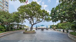 A spacious outdoor area with a central tree, seating arrangements, and a modern building in the background. - Family friendly unit with fabulous Ocean/Lagoon view  (Honolulu)