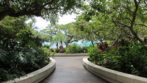 A paved pathway surrounded by lush greenery and a view of the sea. - Family friendly unit with fabulous Ocean/Lagoon view  (Honolulu)