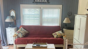 A cozy room with a red sofa, a white cabinet, and a sign that reads 'RELAX'. - Great Location, Beach 4 minutes walk, Large Patio and Parking for one vehicle. (Dennis)