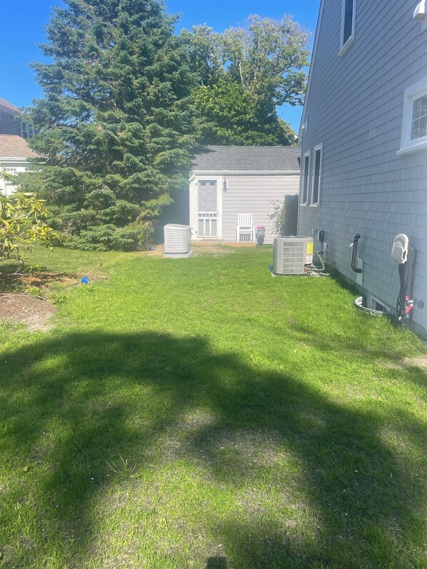 A residential yard with a lawn, a house, and a large tree.