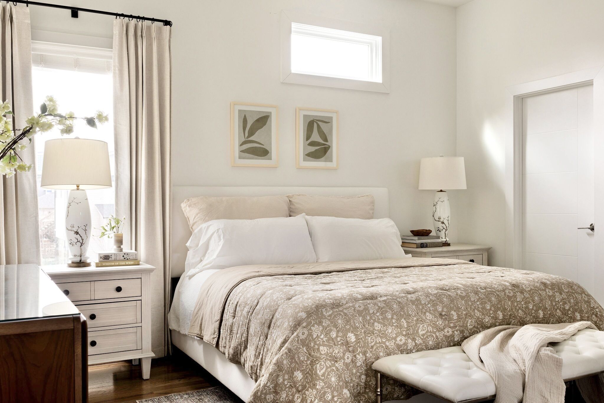 A bedroom with a bed, bedside tables, a bench, and a window with curtains.