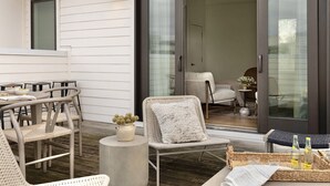 Une terrasse extérieure aménagée avec des meubles en osier, une table à manger et une porte-fenêtre coulissante donnant sur un espace intérieur.