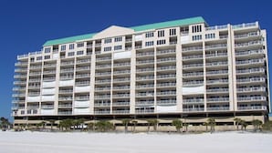Un hotel de varios pisos con balcones, situado en una playa de arena.