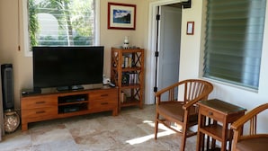 Una sala de estar con televisor, mueble de entretenimiento de madera, estantería y un letrero que dice 'BEACH HOUSE'.
