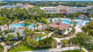A resort with multiple swimming pools, palm trees, and a large building in the background.