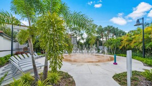 A landscaped area with a fountain, benches, and a pathway.