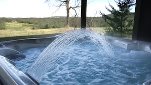 Un bain à remous dans lequel l’eau s’écoule, entouré d’un paysage rural.