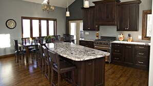 Une cuisine moderne avec des meubles de couleur bois foncé, un îlot en granit et une grande fenêtre.