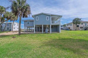 A two-story house with a covered porch and a small balcony, surrounded by grass and palm trees. - 4 bedrooms, Ocean Views, fireplace, entertainment room with large screen tv! (Edisto Beach)