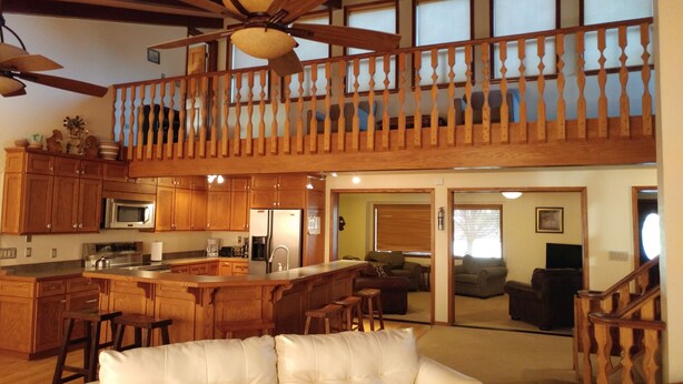 Una cocina amplia con armarios de madera, una isla grande y una zona de comedor con un sofá blanco.