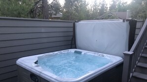 Ett bubbelbad med en bänk och ett överbyggt område, omgivet av ett trädäck och en trappa.