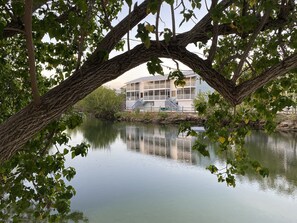 Overlooking a serene lake, this two-story retreat features a spacious balcony and is surrounded by lush greenery.