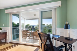 Enjoy a spacious room with a sliding glass door leading to a balcony, a desk with a computer monitor, and a comfortable chair.